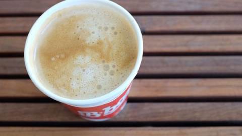 A cup of coffee sits on a wooden bench in Berkeley, CA.