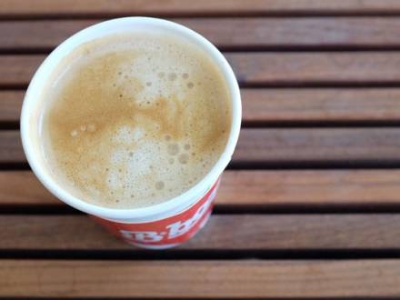 A cup of coffee sits on a wooden bench in Berkeley, CA.