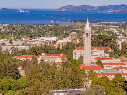 aerial view of the Berkeley skyline featuring red roof buildings and a clock tower with the bay in the distance