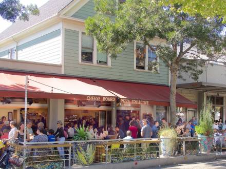 A large crowd gathers outside of Cheese Board Pizza Collective near North Berkeley BART Station