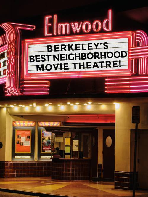 Pink white and black marquee sign for the Elmwood movie theatre illuminated at night in Elmwood, Berkeley, CA