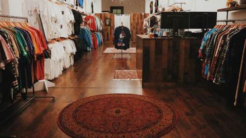 interior of Paisley Vintage, a Berkeley thrift store, with neatly organized clothing lining both sides of the store