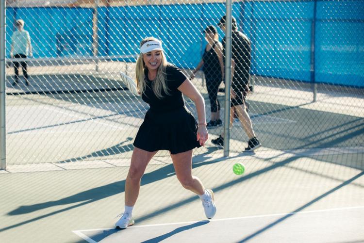 A woman moves to hit the ball during a pickleball match