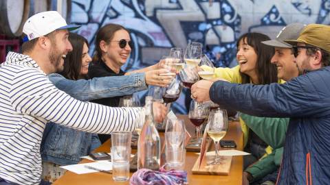 Group at outdoor table eating lunch and holding up drinks to toast in Berkeley Ca
