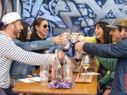 Group at outdoor table eating lunch and holding up drinks to toast in Berkeley Ca
