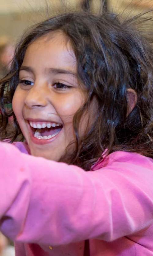 a child in a pink sweater touches a mirrored orb at the Lawrence Hall Of Science in Berkeley, CA