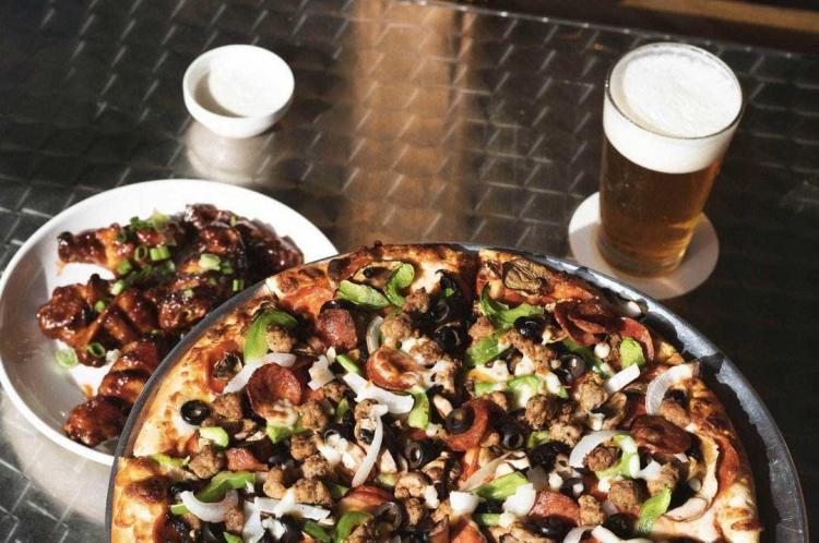 A pizza and beer on a table at Red Tomato Pizza House