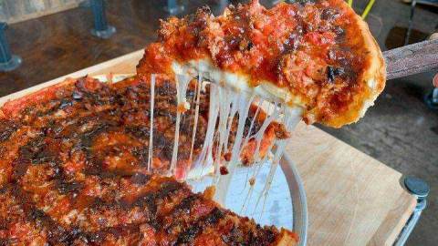 A slice of pizza from Zachary's Chicago Pizza being pulled from a larger pie.