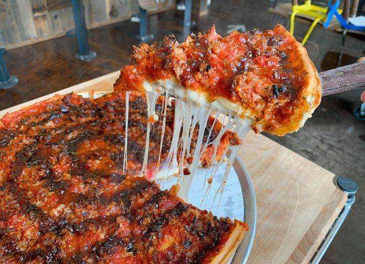 A slice of pizza from Zachary's Chicago Pizza being pulled from a larger pie.